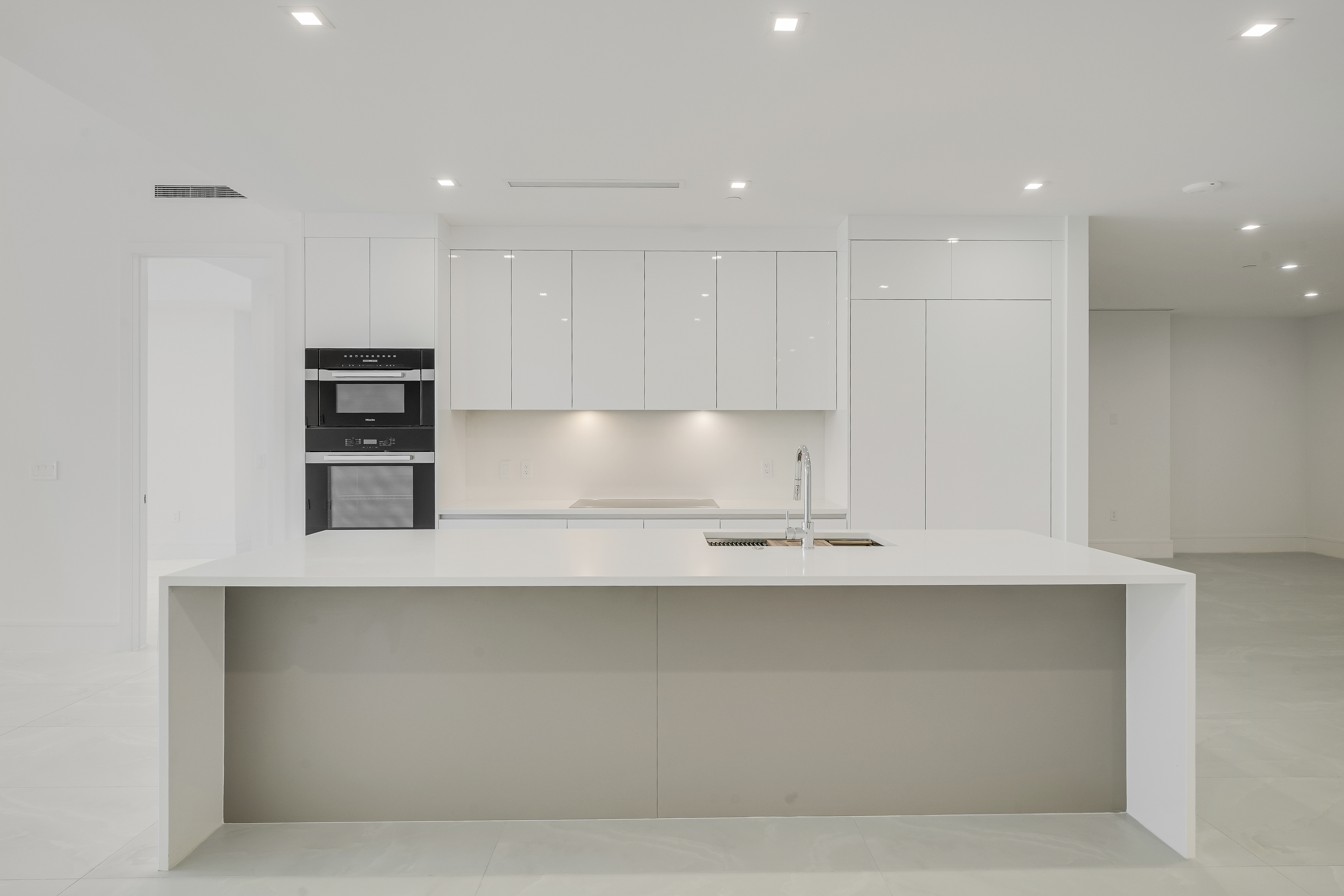 Sleek white kitchen with oversized island and integrated appliances in Executive 704