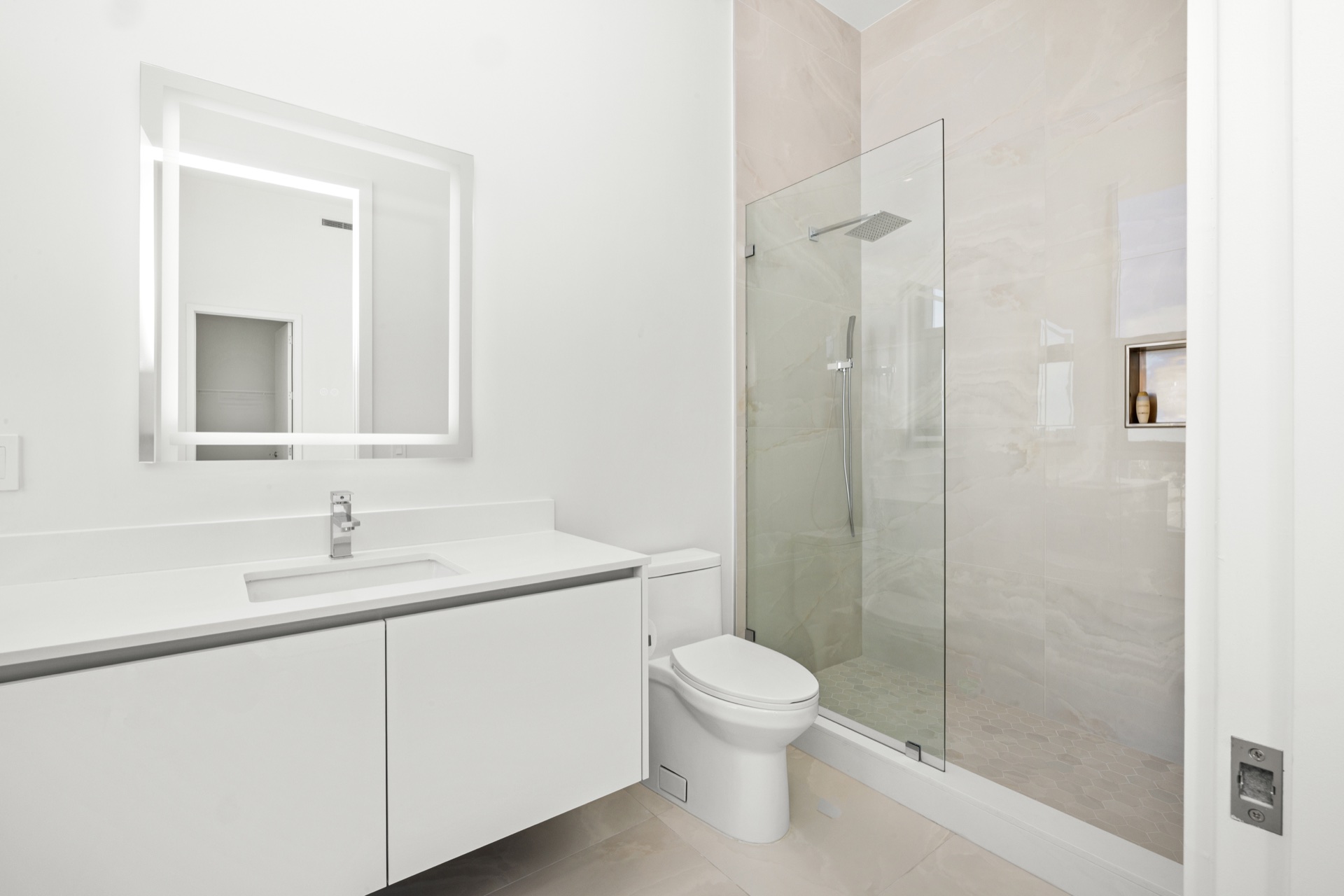 Guest bathroom with illuminated mirror and glass shower in Residence 612